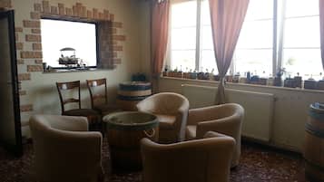 A room with a brick wall, a window with curtains, and several chairs.