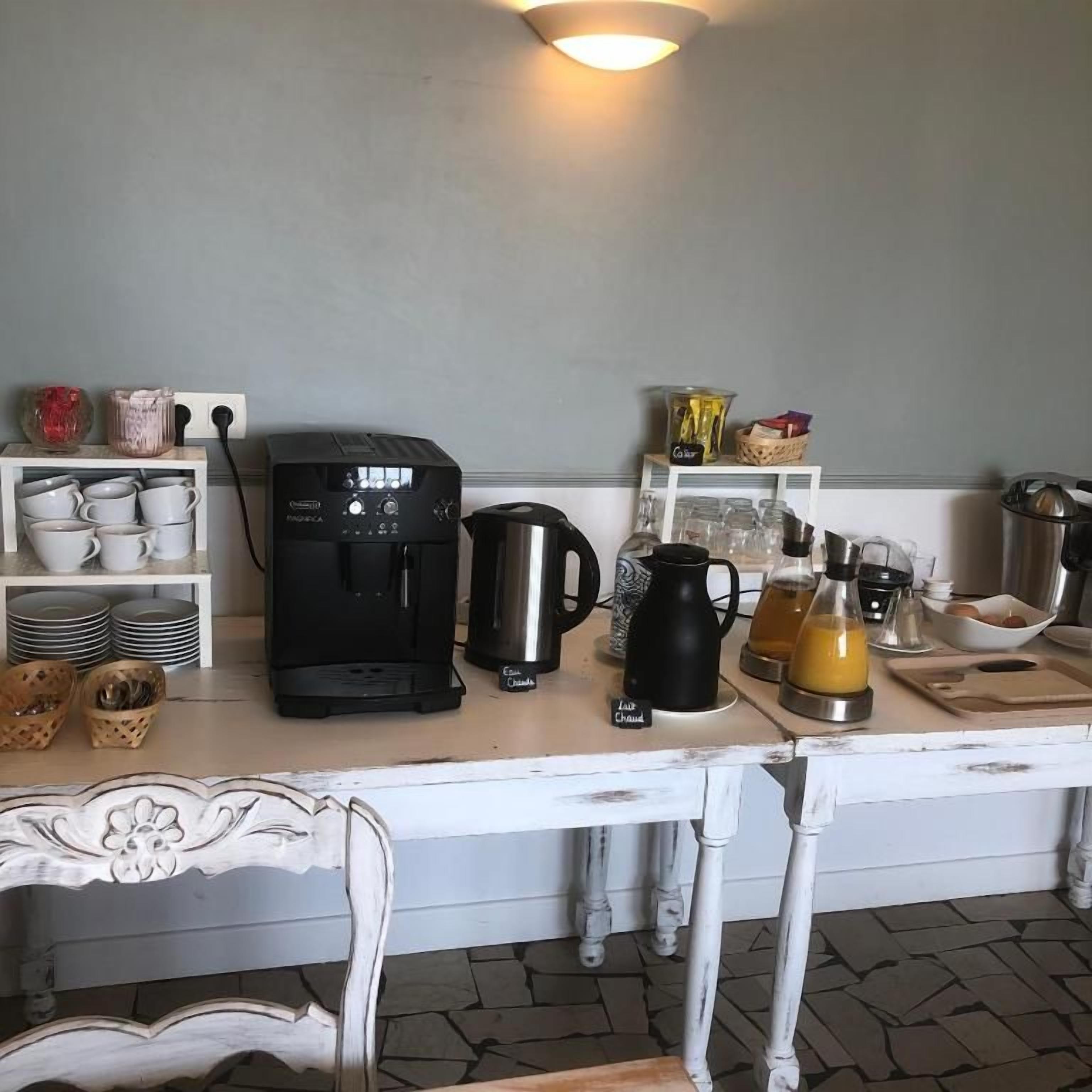 Una cocina con cafetera, hervidor y diverso menaje de cocina sobre la encimera.