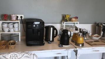 Una cocina con cafetera, hervidor y diverso menaje de cocina sobre la encimera.
