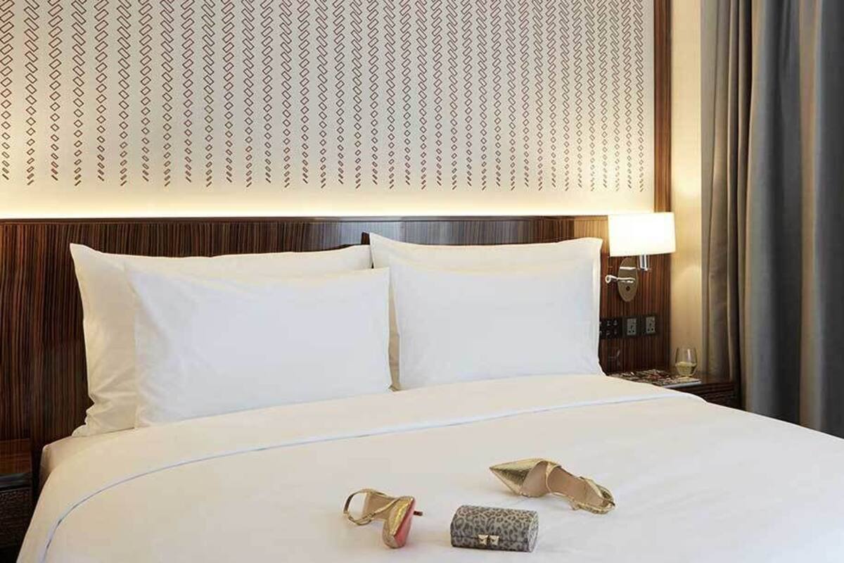Et hotelværelse med en stor seng, et natbord med en lampe og udsigt til det fri.