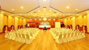 Uma sala de conferências com fileiras de cadeiras, um púlpito e palco com tela.