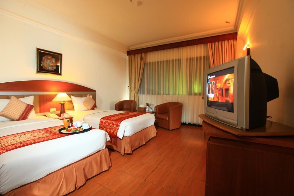 A hotel room with two beds, a television, a desk, and a chair.