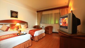 Quarto de hotel com duas camas, televisão, escrivaninha e uma cadeira.