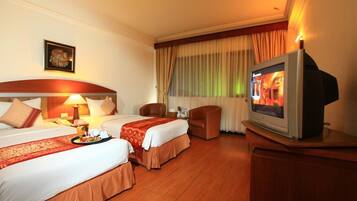 A hotel room with two beds, a television, a desk, and a chair.