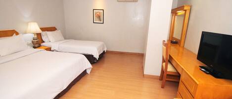 A hotel room with two beds, a desk with a television, a chair, a lamp, and a picture on the wall.