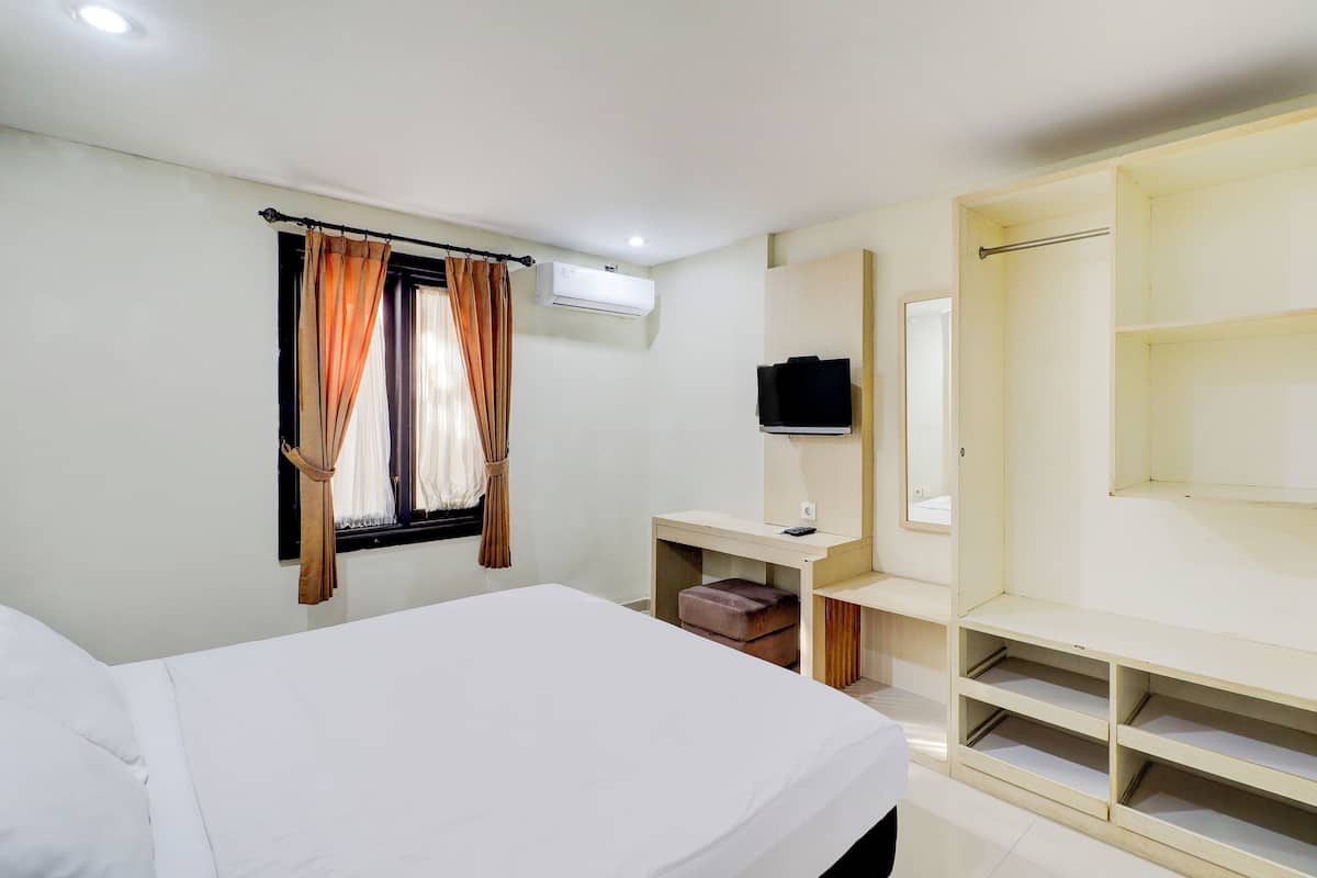Ein Hotelzimmer mit Bett, Schreibtisch mit Stuhl, Fernseher und Kleiderschrank.