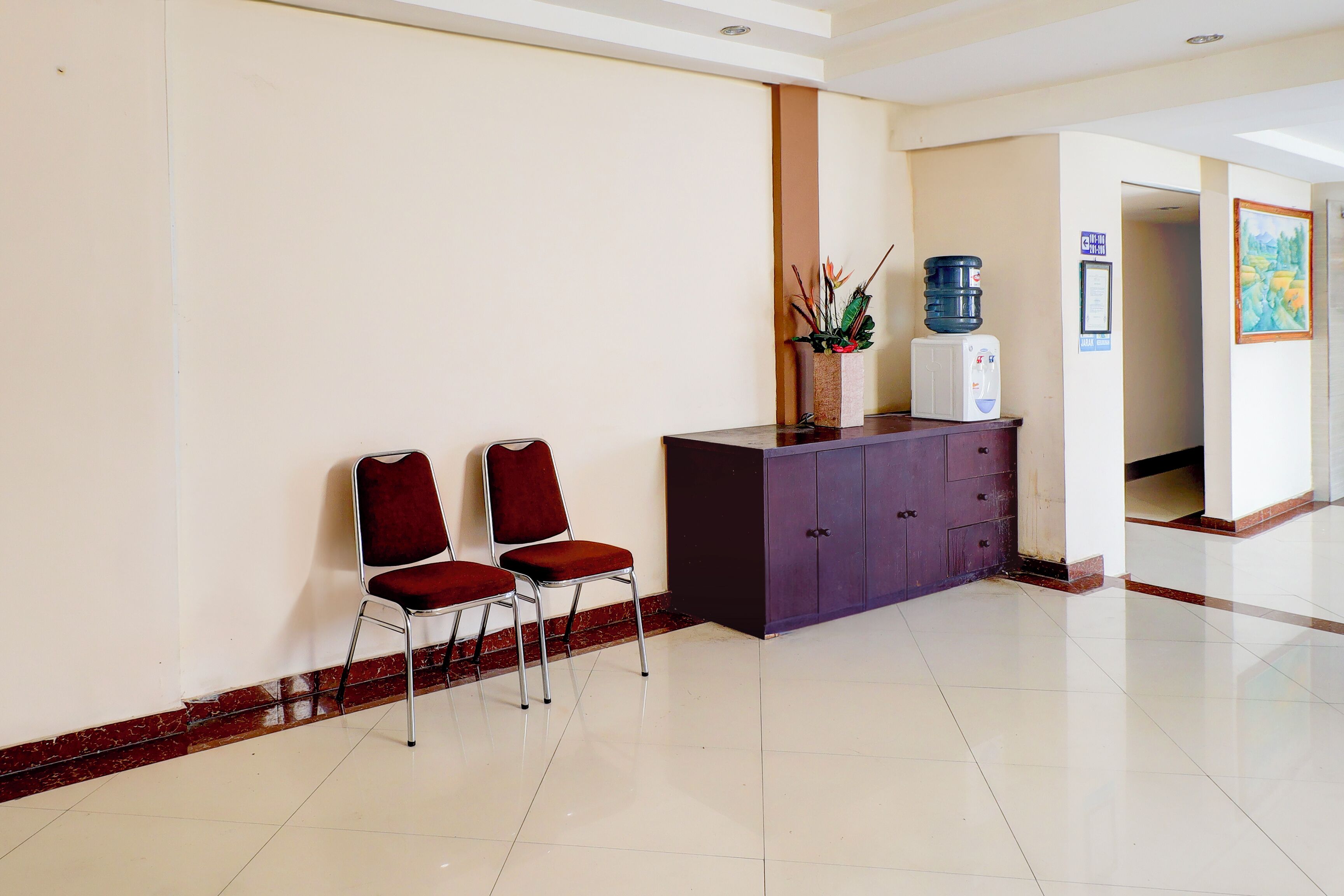 A reception area with two red chairs, a purple counter, a water dispenser, and a framed certificate on the wall.