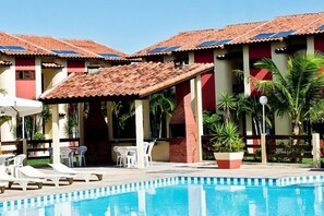 Uma área de piscina com espreguiçadeiras e um espaço de estar coberto.
