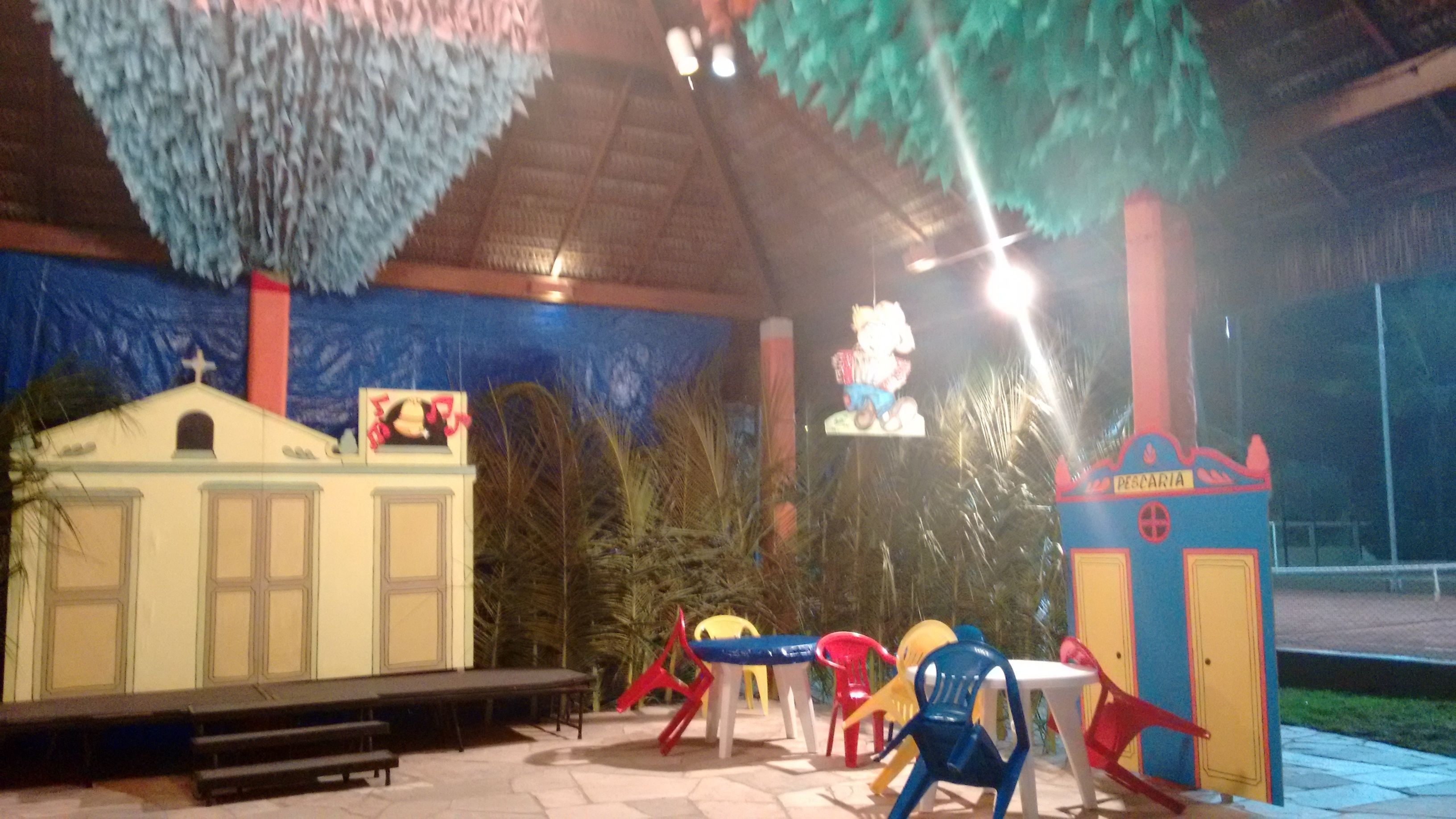 A covered outdoor area with a stage, seating, and colorful play structures.