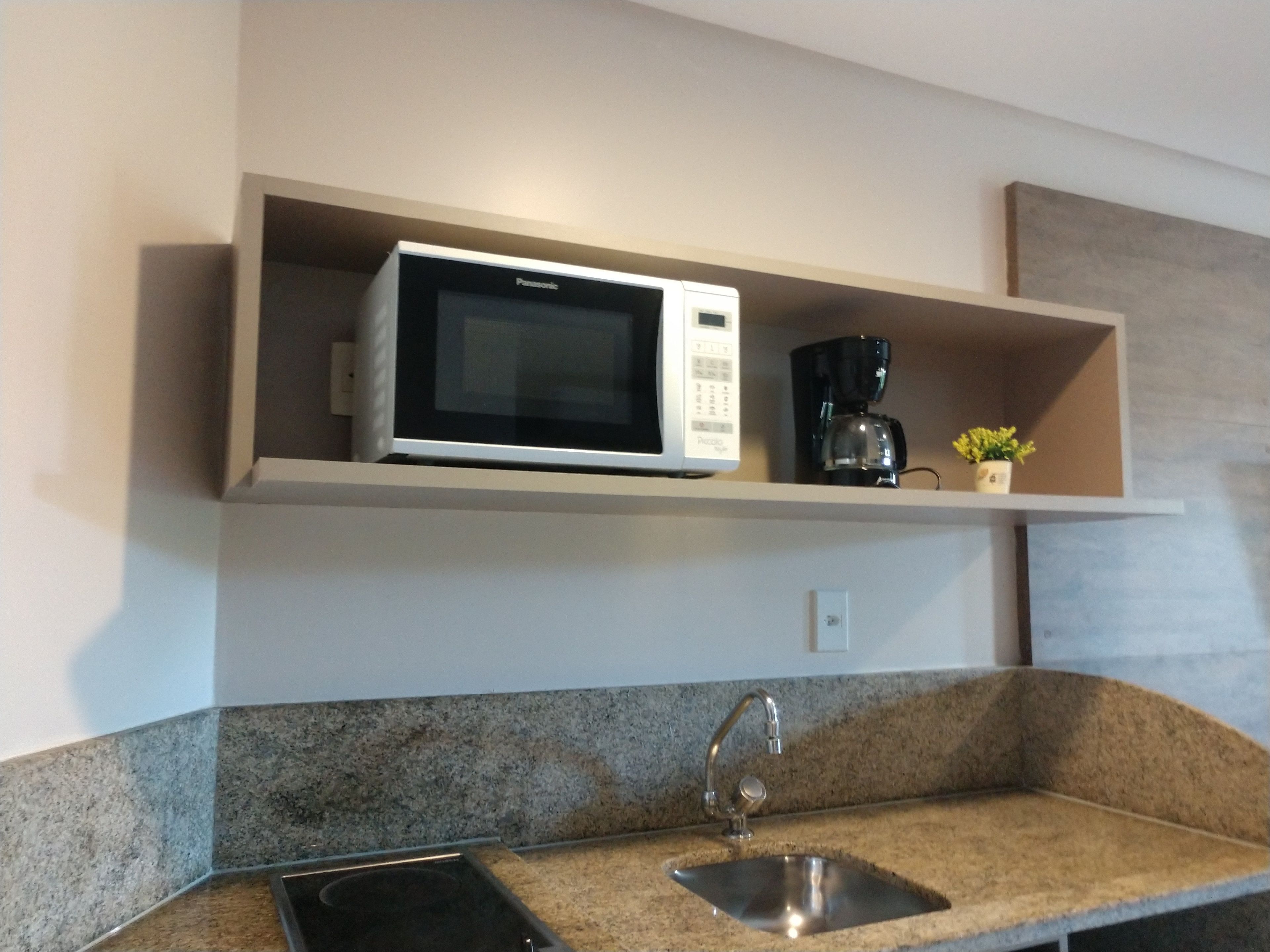 A kitchen with a microwave, coffee maker, and a sink.