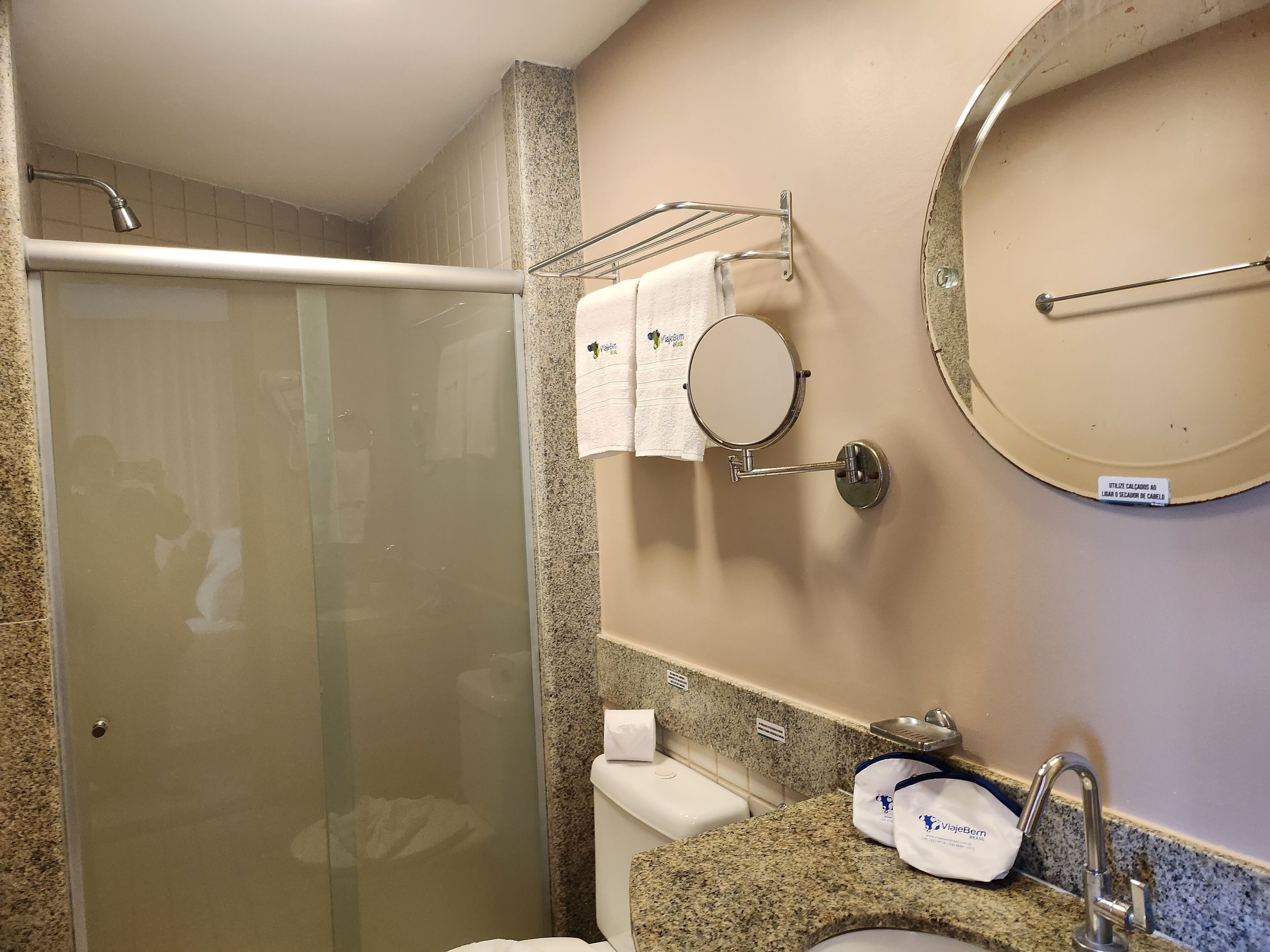 A bathroom with a glass-enclosed shower, a sink with a towel rack, and a mirror.