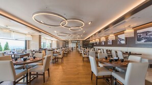 A spacious restaurant with modern decor, featuring a long counter with tables and chairs, and a ceiling with circular light fixtures. - Radisson Blu Hotel, Ordu (Ordu)