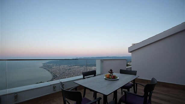 A balcony with a table and chairs, overlooking a coastal cityscape during sunset. - Radisson Blu Hotel, Ordu (Ordu)