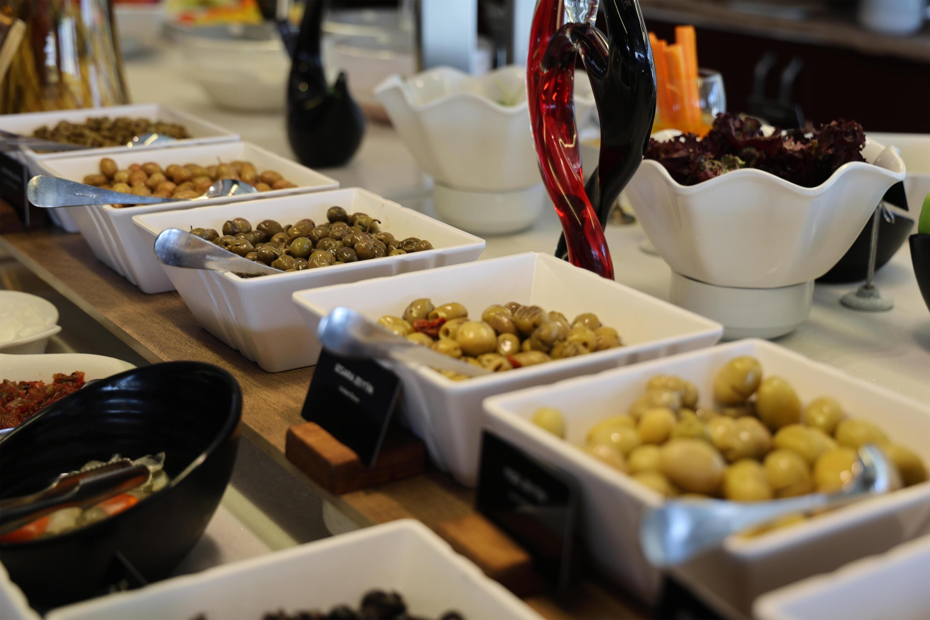 A buffet table with various dishes including olives, nuts, and salads.