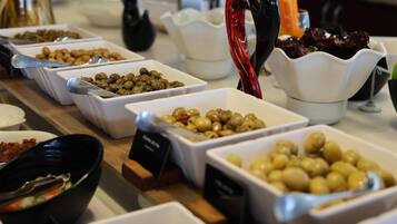A buffet table with various dishes including olives, nuts, and salads.