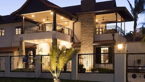 A two-story house with a balcony, a stone pillar, and a well-lit entrance.
