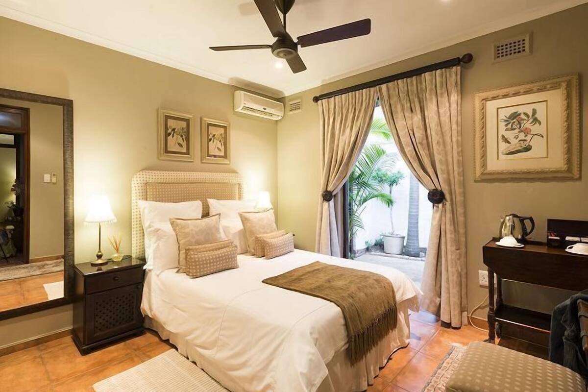 Un dormitorio con cama, mesitas de noche, escritorio y ventilador de techo.