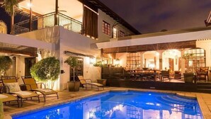 A two-story building with a swimming pool, outdoor seating, and a balcony.