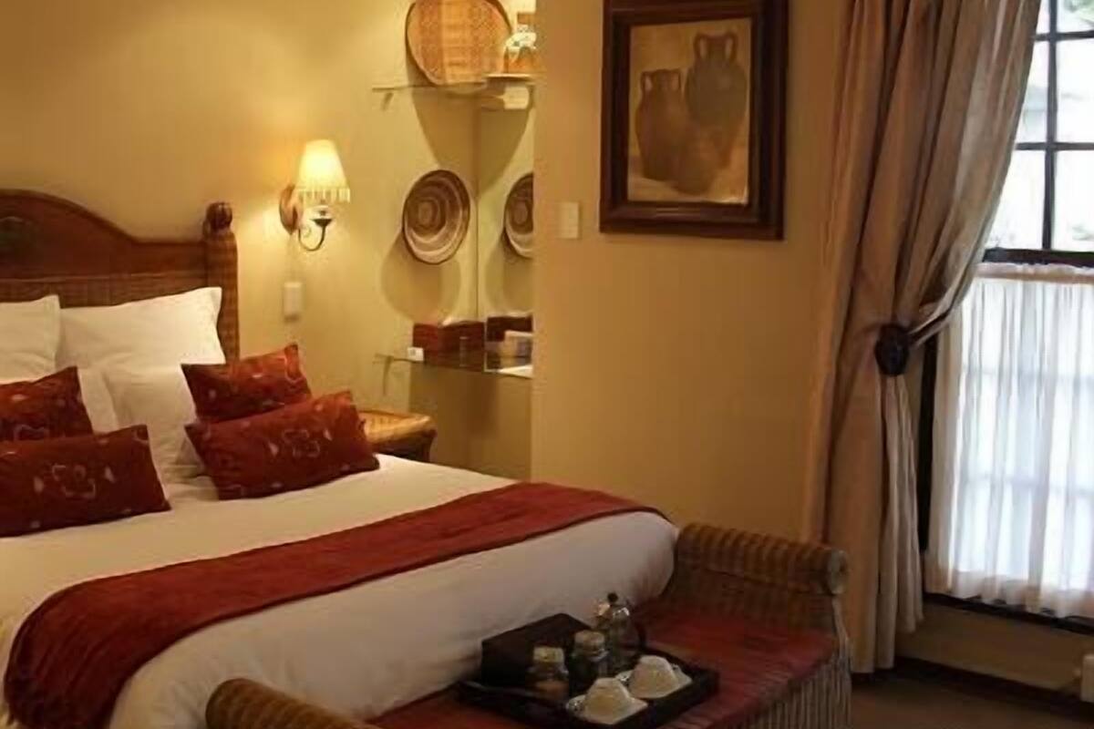 Habitación de hotel con cama, ventilador de techo, ventana con cortinas y aire acondicionado instalado en la pared.