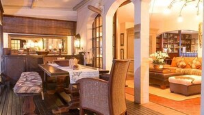 A cozy interior with a dining area, a seating area with a sofa and ottoman, and a bookshelf.