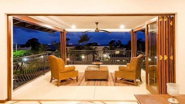 A balcony with two wicker chairs, a small table, and a glass door leading outside.