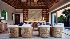 A lounge area with wicker furniture, a bar, and a large window overlooking a pool. - Casa Chablé Sian Ka'an Reserve - South of Tulum (Punta Allen)