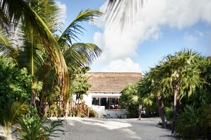 A beachside resort with a thatched-roof building, surrounded by palm trees and a sandy beach.