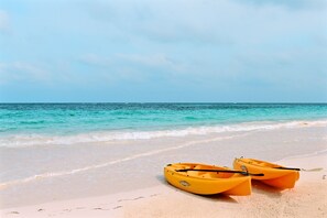 A beach with two yellow kayaks on the sand.