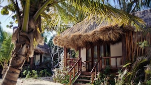 A thatched-roof bungalow with a wooden staircase leading to a porch, surrounded by tropical vegetation and palm trees. - Casa Chablé Sian Ka'an Reserve - South of Tulum (Punta Allen)