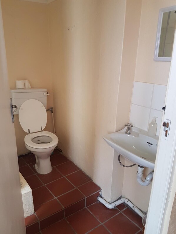 A small bathroom with a toilet, sink, and tiled floor.