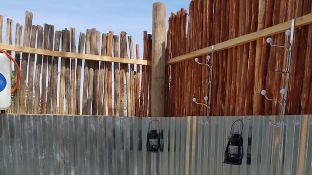 Un espacio al aire libre cercado con un banco de hormigón y una pequeña mesa, rodeado de guijarros blancos y follaje.