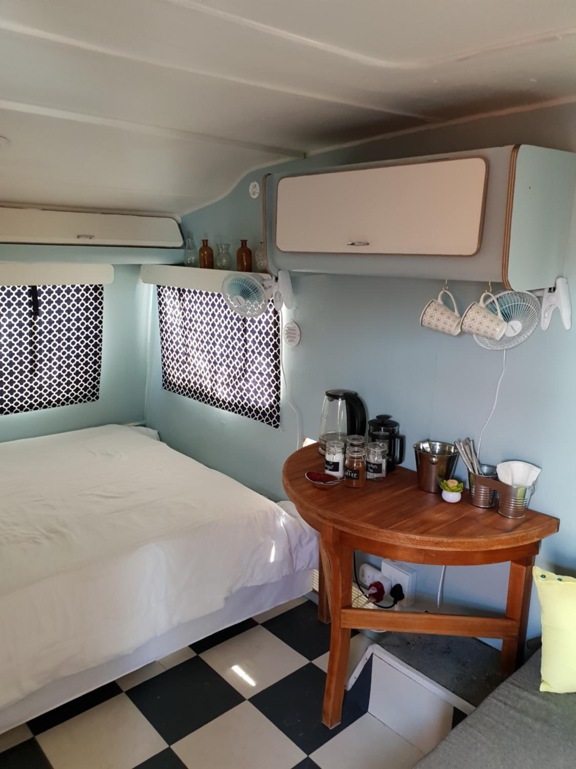 Une chambre de taille réduite comprenant un lit, une petite table avec le matériel nécessaire pour préparer du café et un coin cuisine.