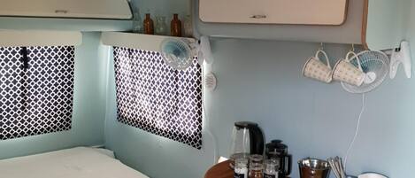 Une chambre de taille réduite comprenant un lit, une petite table avec le matériel nécessaire pour préparer du café et un coin cuisine.