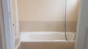 A bathroom with a bathtub, toilet, and a shower.