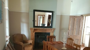 Un comedor con una mesa y sillas de madera, una chimenea y un espejo encima.
