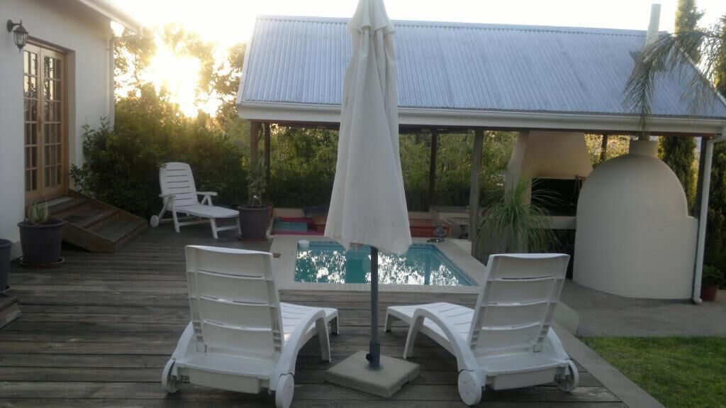 A poolside area with lounge chairs, an umbrella, and a covered patio.