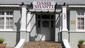 Un edificio con un cartel que dice 'Oasis Shanti Backpackers Guest House'.