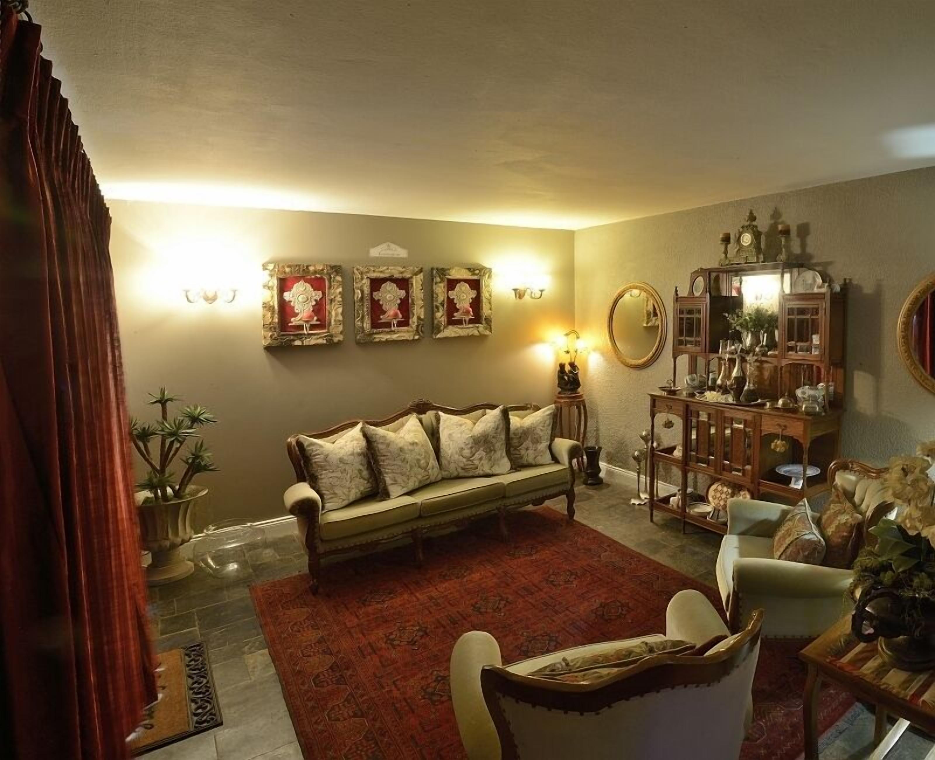 Ein gemütliches Wohnzimmer mit einer Couch, Sesseln, einem Couchtisch und einer Kommode mit Dekoration.