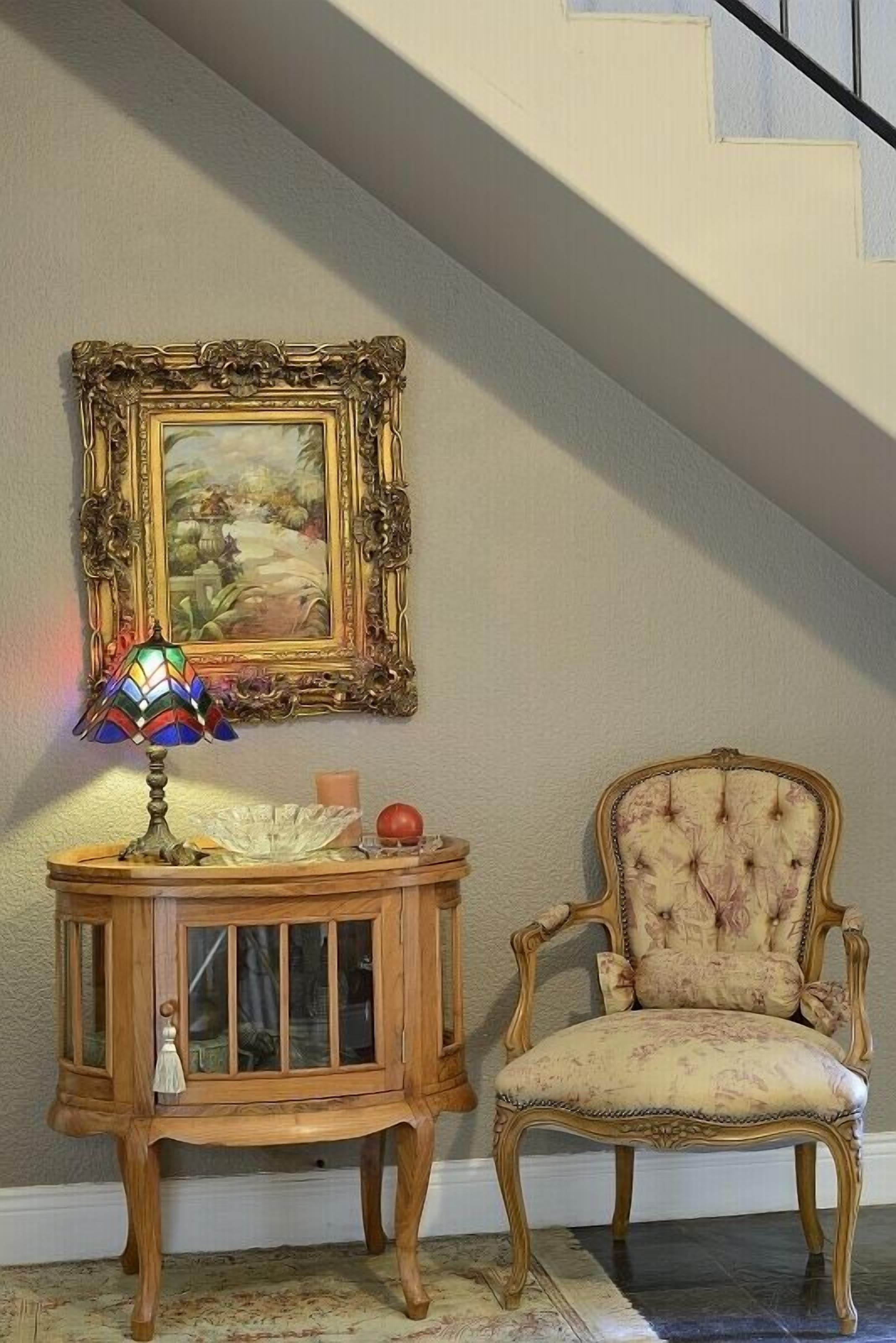 A staircase with a wooden chair and a side table with a lamp and a candle.