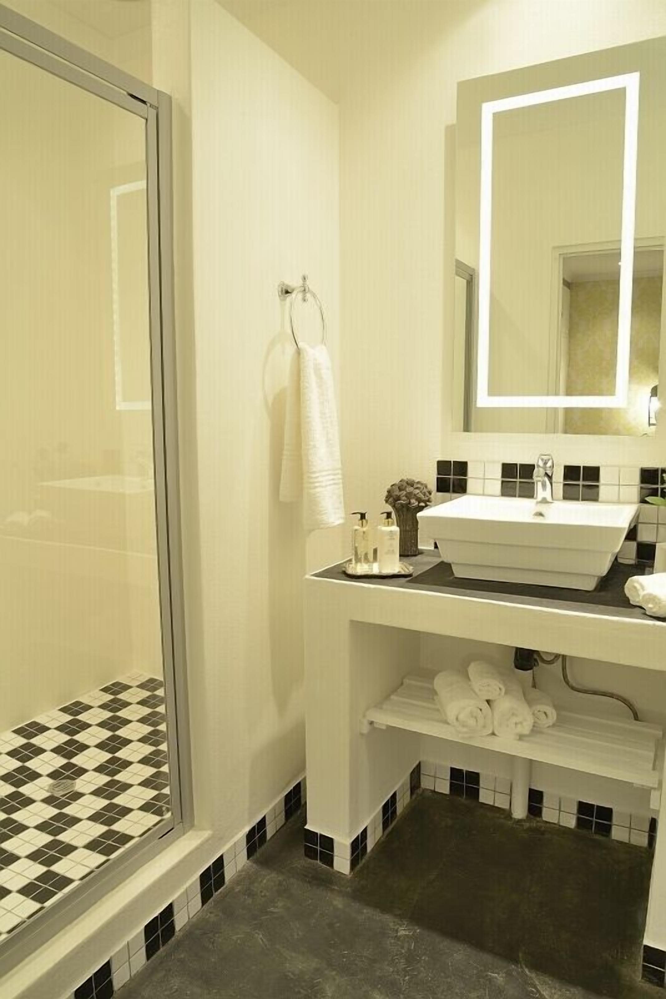 Un bagno con cabina doccia in vetro, un lavandino bianco con piano d'appoggio nero e uno specchio sopra il lavandino.