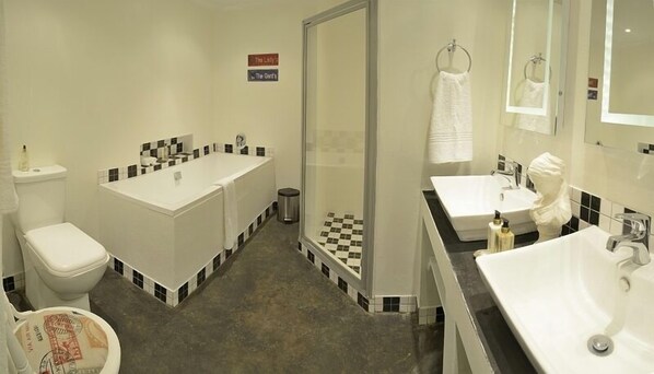 A bathroom with a bathtub, toilet, and two sinks.