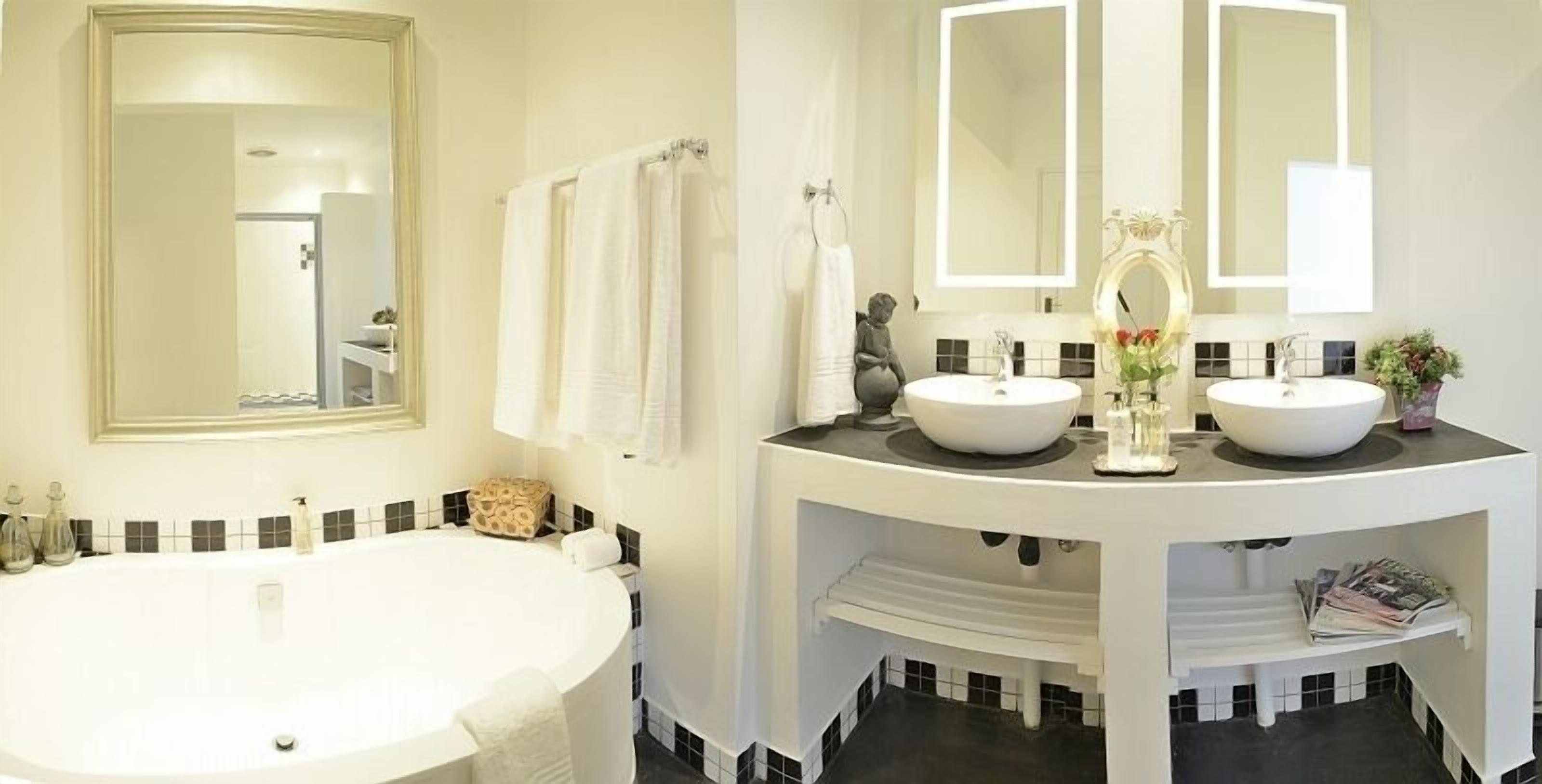 A bathroom with a large bathtub, two sinks, and a vanity with a mirror.