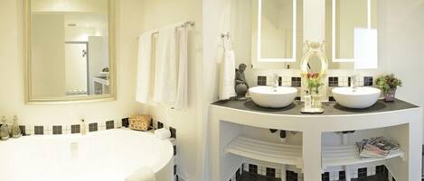 A bathroom with a large bathtub, two sinks, and a vanity with a mirror.