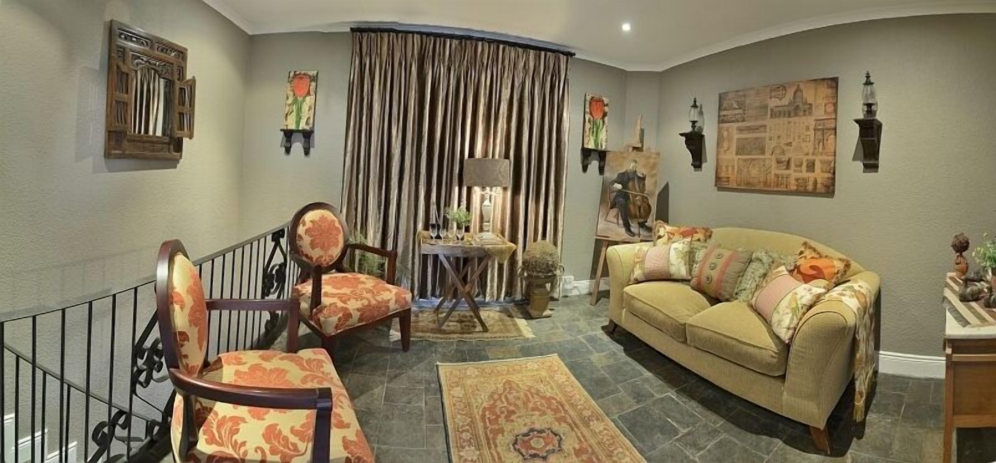 Una sala de estar con sofá, sillón y una mesita con lámpara.