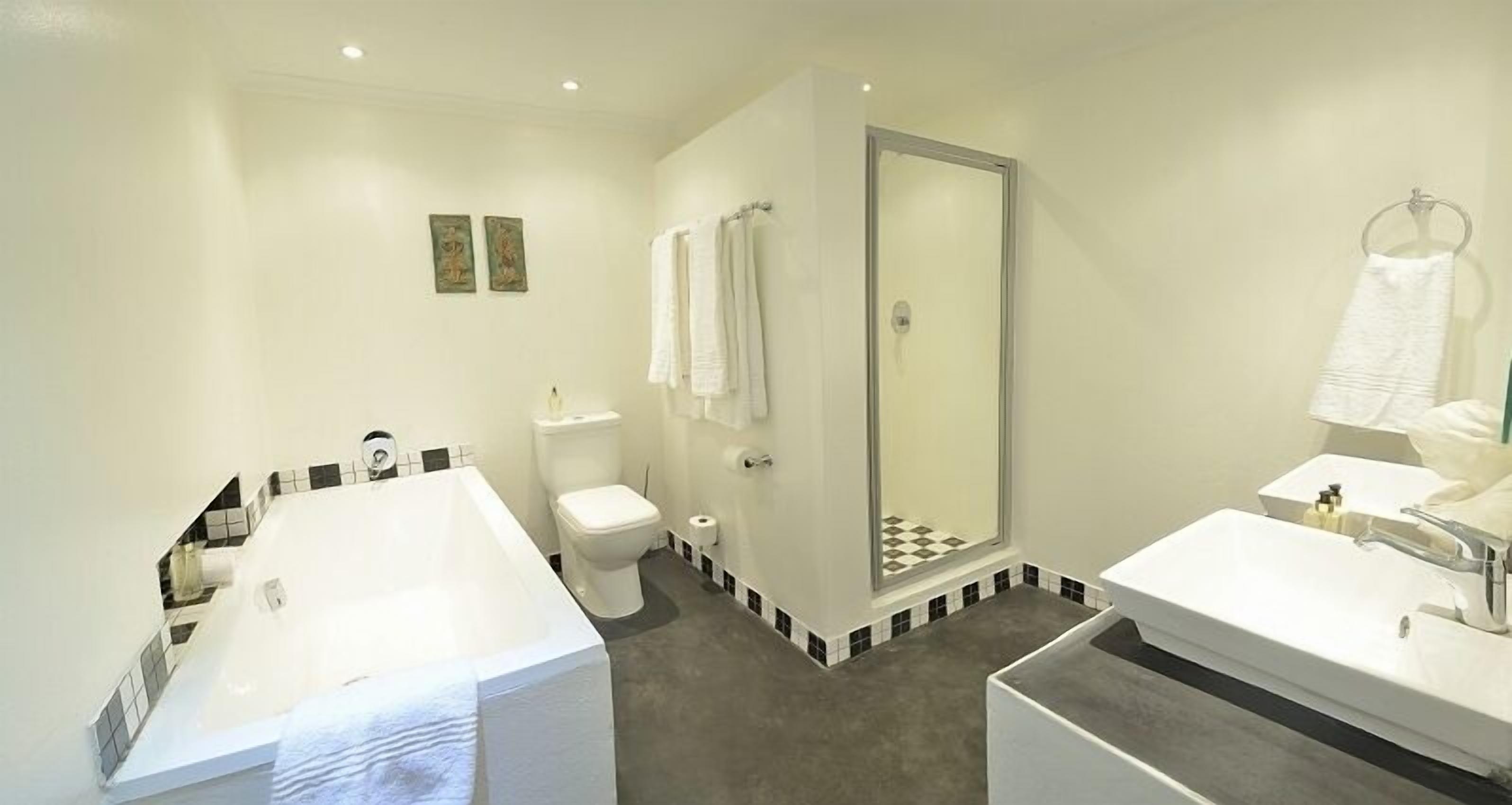 A modern bathroom with a bathtub, toilet, shower, and sink.