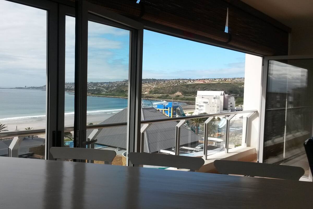 Una habitación con un ventanal grande que da a una playa y una torre de salvavidas.
