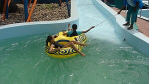 Un toboggan aquatique avec un tube jaune et deux personnes à l’intérieur.