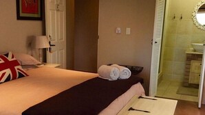 A bedroom with a bed, a bedside table, a lamp, a rolled-up towel, and a small white cabinet. - Hamelin Guest House (Bluff)