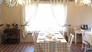A dining area with a checkered tablecloth, white chairs, and a chandelier. - Hamelin Guest House (Bluff)