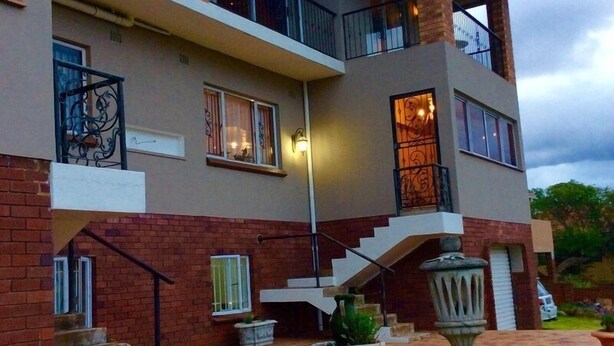 A multi-story building with a central staircase, balconies, and a paved courtyard. - Hamelin Guest House (Bluff)